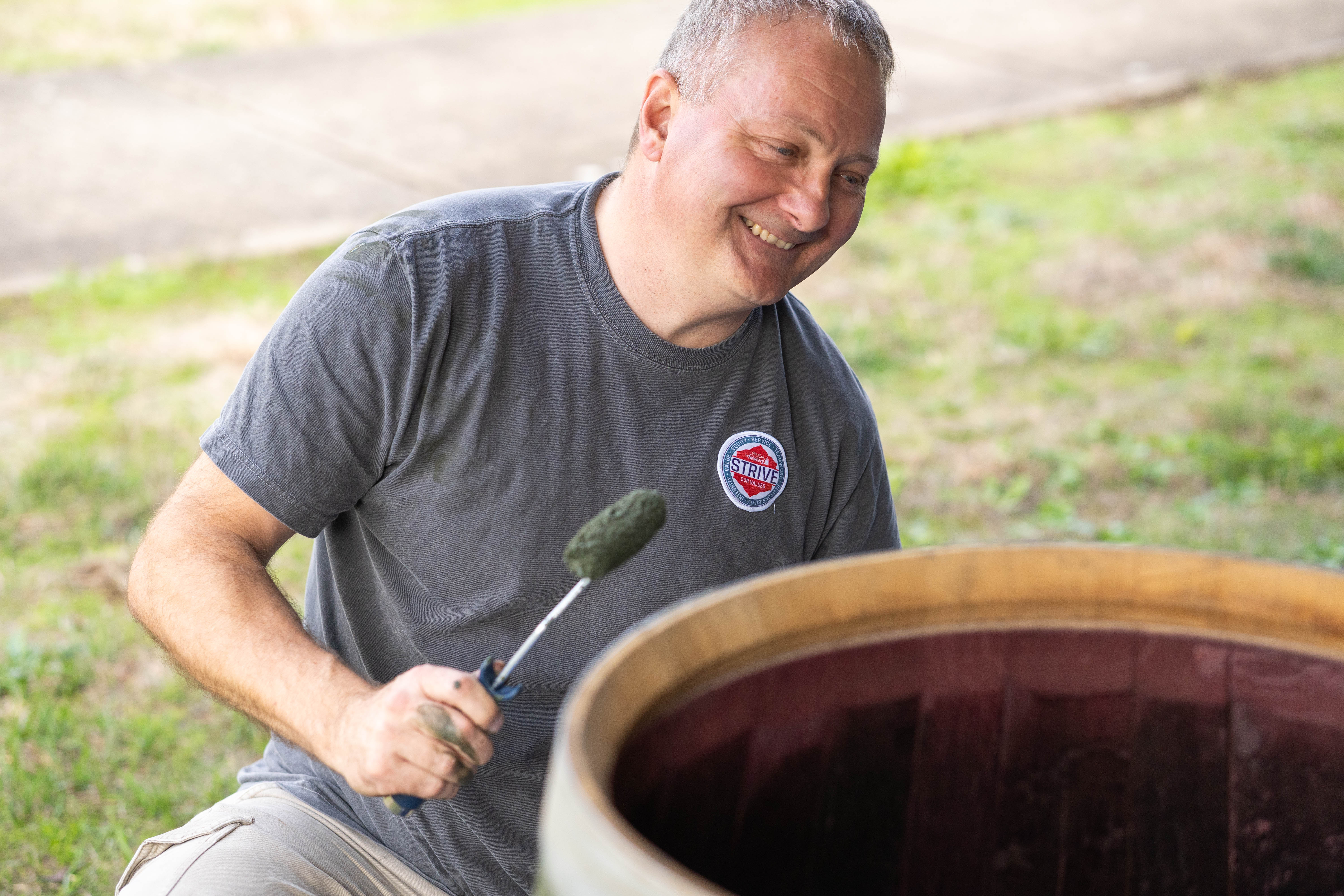 Newberg City Manager Will Worthey paints barrels that will house plants in downtown Newberg as part of the city's beautification initiative. (Branden Andersen / Newsberg)